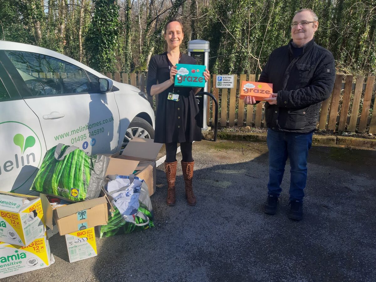 Fiona Williams o Melin a Paul Stephens-Warburton o Helping Hands R Us yn y llun yn dal pecynnau bwyd amrywiol