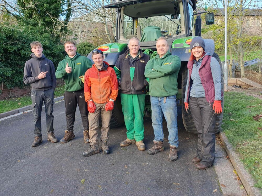 A group of people in work clothes stood by a tractor