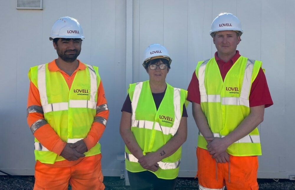 Three workers stood in a line wearing building site PPE
