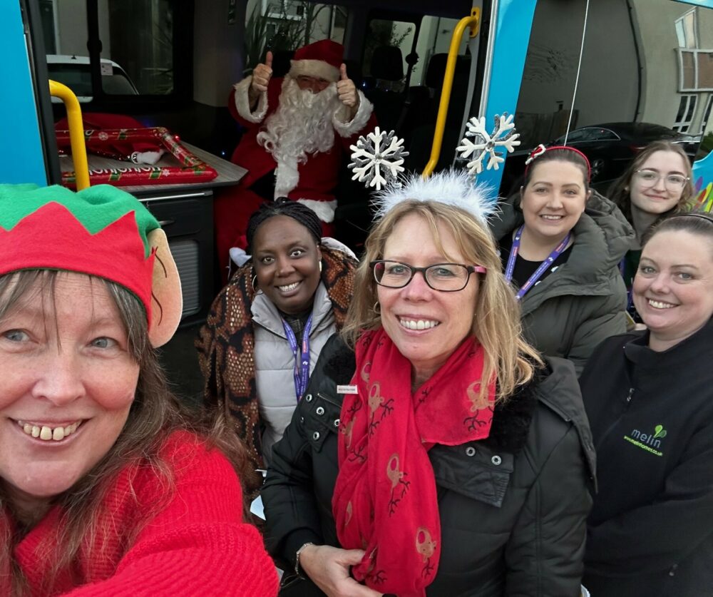 A group of people (and Santa) posing for a selfie photo