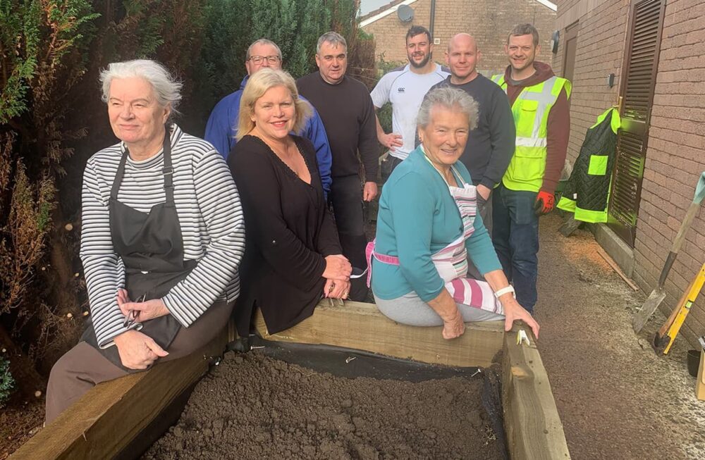A group of people sat around a raised garden bed