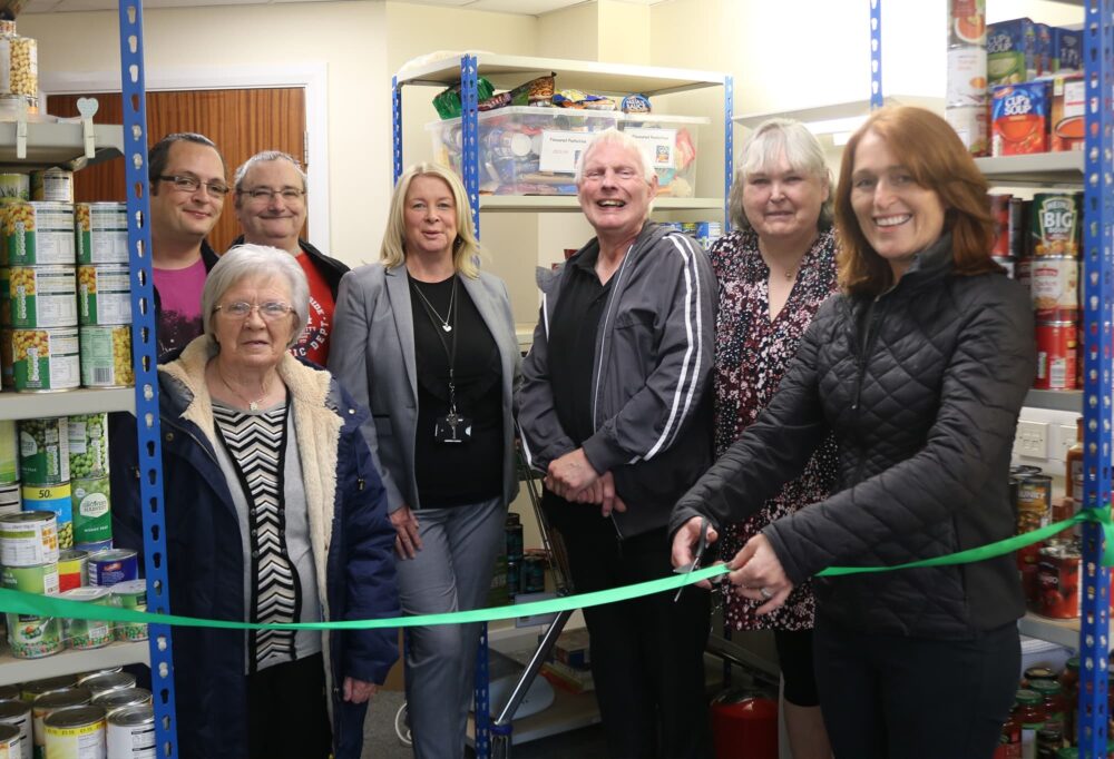A photo of Carol, Kyle, Paul, Teri, Paul, Jan and Paula cutting a ribbon in the foodback