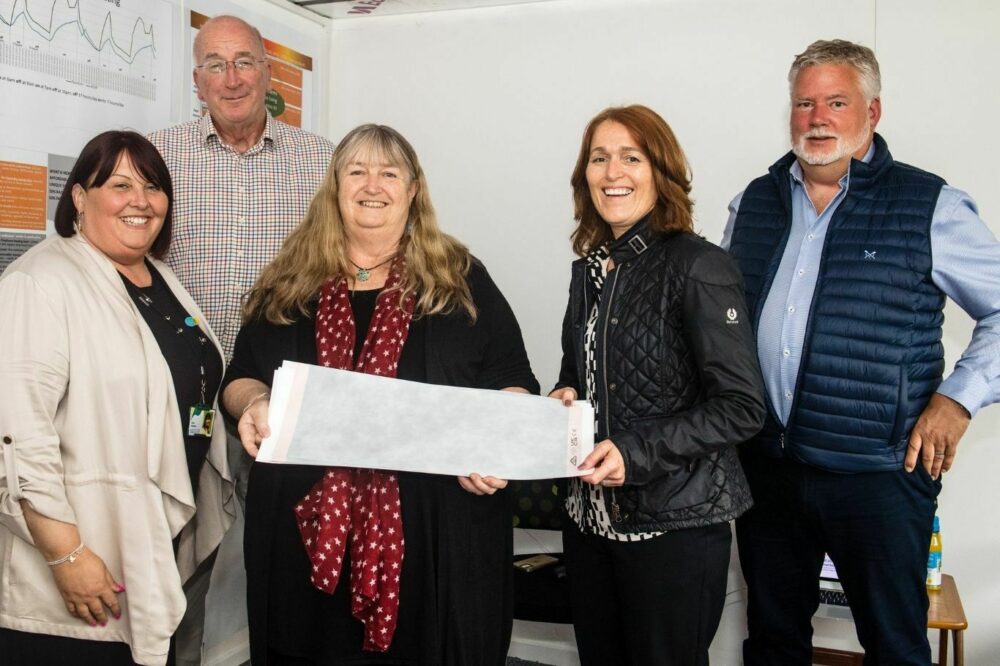 The minister and some of Melin staff holding a sample of wallpaper