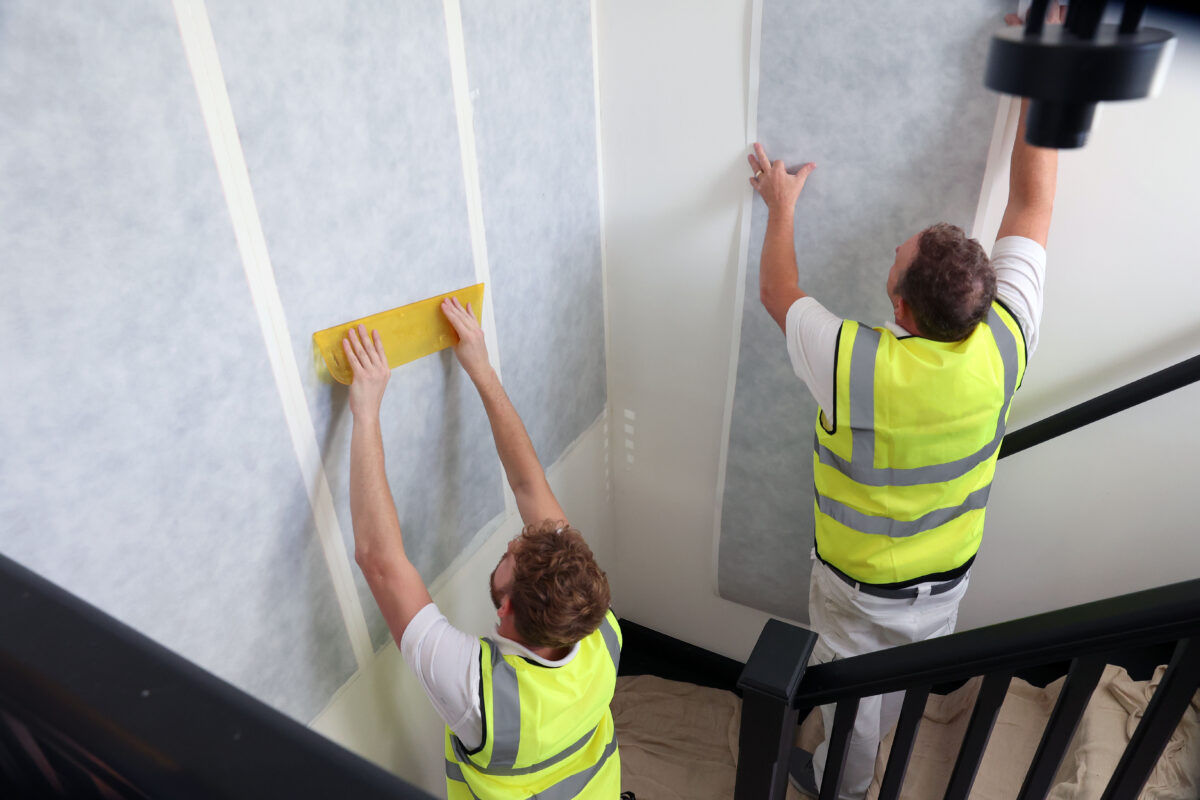 people putting up wallpaper that heats the room