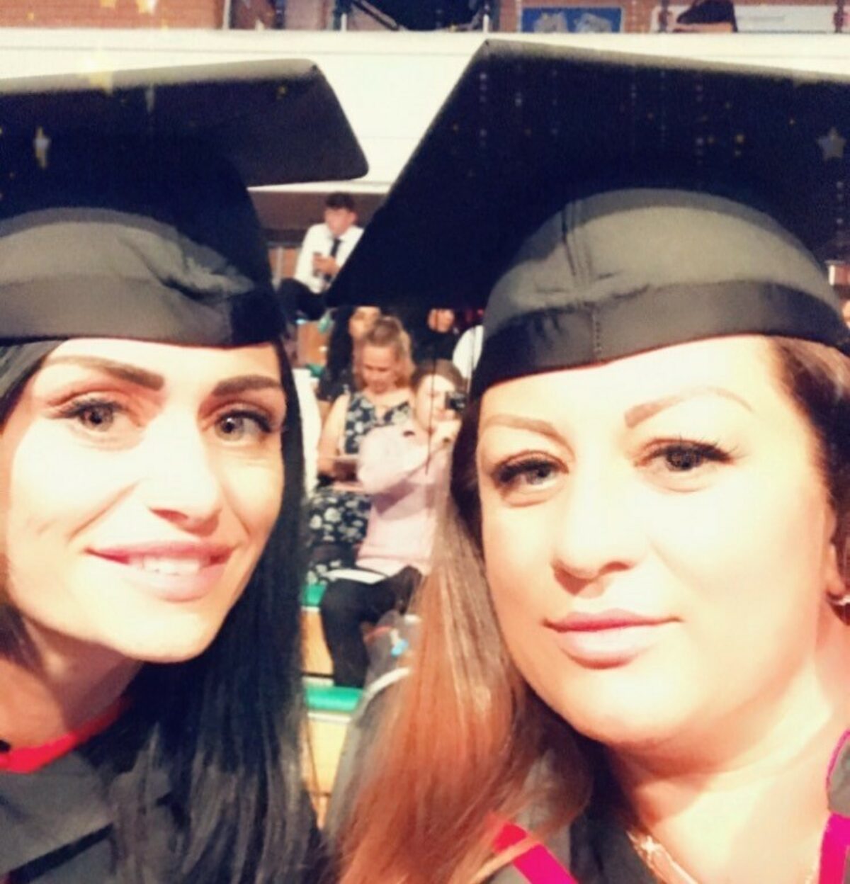 Dwy ddynes yng ngwisg graddio