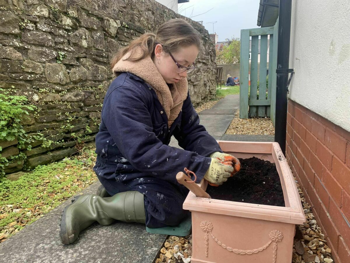A college student putting fresh compost into a planter